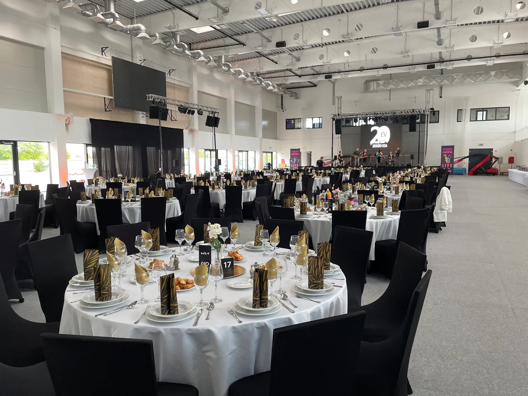 A large event hall with round tables and a stage